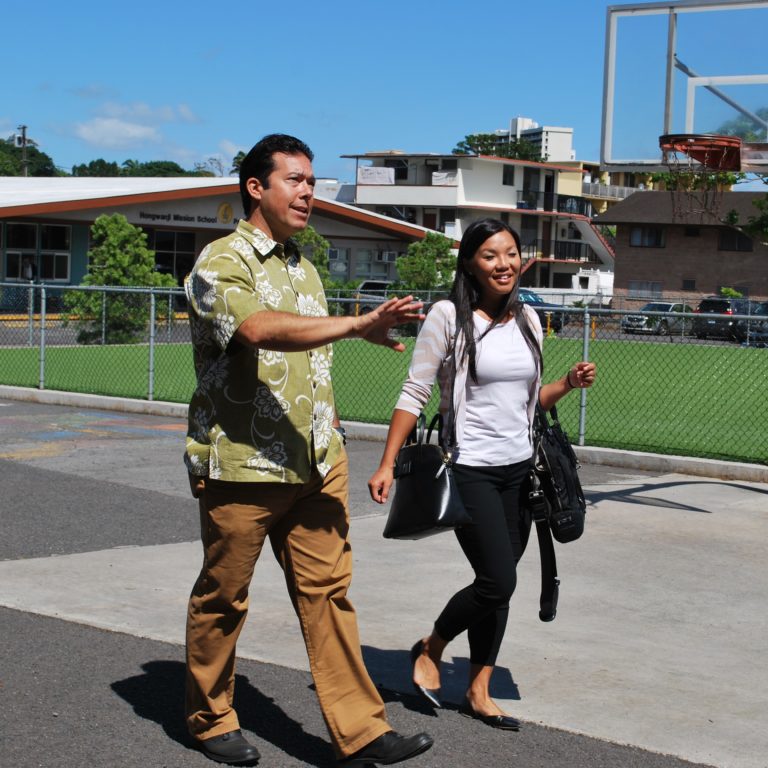 man and woman walk near basketball court in Hawaii