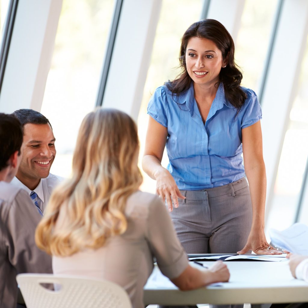 standing woman leads discussion with professional team