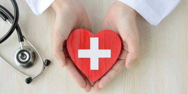 Hands holding red cross heart and stethoscope